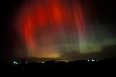 Blood red streaks of Aurora Borealis over a farm