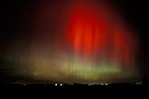 Streaky red and green northern lights) over farm lights