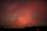 A blushing night sky with patchy red and green Aurora Borealis