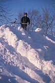 A young boy stands atop a very large snowbank