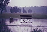 Flooding surrounds a park bench on golf course