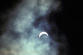 Partial solar eclipse with a crescent sun and eerie clouds