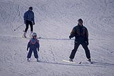 Parents and child skiing on snow-covered ski slope