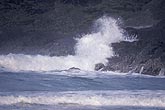 Surf crashes on rocky cliffs sending blowing spray up