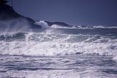 Spray from the churning sea as whitecap waves crash on a rocky coast