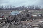 Damaged tractor-trailer upturned in a field of debris after a tornado