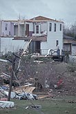 A house ripped open, with twisted satellite dish and tornado debris