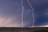 Close lightning strikes against a twilight rain curtain electrify a quiet sky
