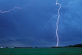 A single close cloud-to-ground lightning strike in the daytime sky