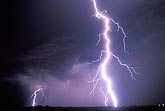 A brilliant, close lightning bolt electrifies the night sky