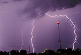 Cloud-to-ground lightning strikes around a tower