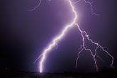 A very close highly electric lightning bolt sears the night sky