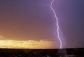 A single brilliant close lightning bolt strikes in a golden sunset