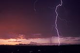 A single lightning bolt strikes in a blood-red desert sky