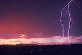 A close forked lightning bolt in a deep red sunset sky