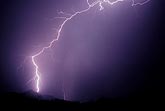 A single brilliant lightning bolt strikes a mountainside