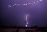 A branching arm of horizontal lightning flashes over a distant bolt
