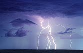 Lightning bolts in a twilight sky with scudding clouds