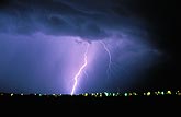 A single brilliant cloud-to-ground lightning strike over city lights