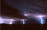 Power bolts of lightning explode below low cloud wedges