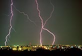 Close-up of cloud-to-ground lightning strikes over city buildings