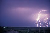 Brilliant lightning bolts approach a country road