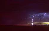 A finely detailed lightning strike against a red and gold sunset sky