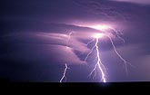 Highly electric forked lightning illuminates a laminar wall cloud