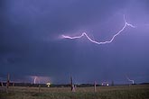 Cloud-to-cloud lightning (intercloud flash) arcs over a field in daylight