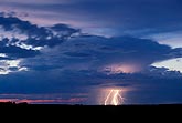 Brilliant lightning and twilight illuminate a backlit Cumulonimbus