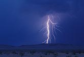 A highly electric lightning bolt strikes the desert at twilight