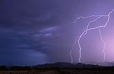 The sky glows blue and purple behind a forked lightning strike
