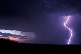 A single, high current lightning bolt burns against a dark storm