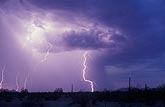 A burst of light brightens clouds while a subtle lightning bolt strikes