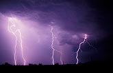 Lightning bolts shine through rain in a stormy sky