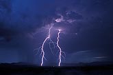 Two brilliant forked lightning bolts in a stormy sky at twilight