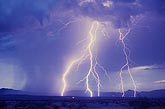 Highly electric daytime lightning strikes in front of mountains 