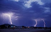 Storm with several hairy lightning bolts sweeps across the desert