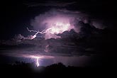 A storm glows with in-cloud flashes and a brilliant lightning bolt