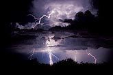 Lightning strikes through clouds illuminated by intracloud flashes