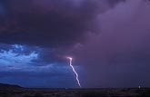 A single lightning bolt knifes through a pink twilight sky