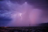 A delicate spear of lightning disappears into gushing pink rain 