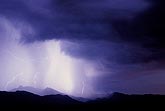Lightning lends a mysterious glow to a mountain rain shower at twilight