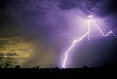 A highly electric lightning bolt burns through a colorful twilight sky