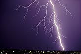 A close lightning bolt strikes over city lights