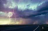 Cloud-to-ground lightning strikes in daylight over a highway