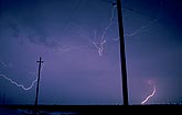 Anvil lightning behind utility poles
