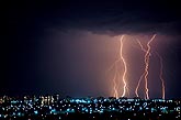 Cloud-to-ground lightning bolts over city skyline
