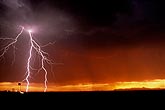 Forked lightning strike with red sky at sunset
