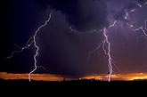 Finely branched lightning strikes with sunset backdrop